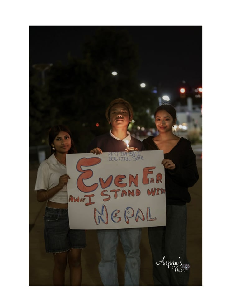 Three young activists holding a protest sign that reads Earthquake wont stand with Nepal at night on an urban street